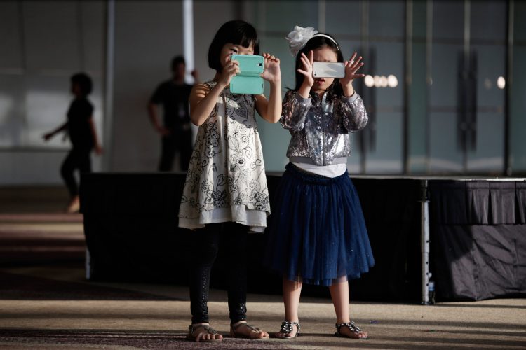 BANGKOK,THAILAND - NOVEMBER 10: Children play with camera phones during the Bangkok International Fashion Week at Siam Paragon November 10, 2013 in Bangkok, Thailand.  (Photo by Paula Bronstein/Getty Images)