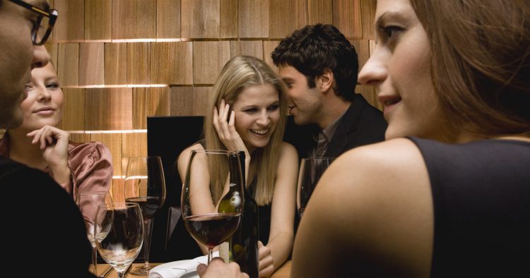 Young man whispering in woman's ear at party